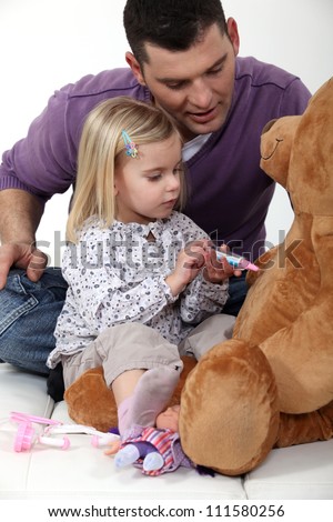 Man with little girl playing with teddy bear
