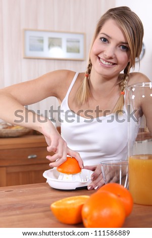 Blond woman freshly squeezing orange juice