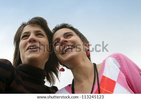 Friends laughing against a blue sky