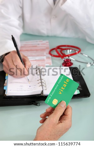 Patient handing social security card to doctor