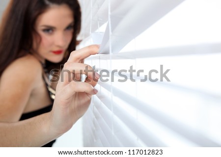 Woman peeking through venetian blinds