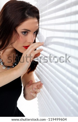 Woman peering through venetian blinds