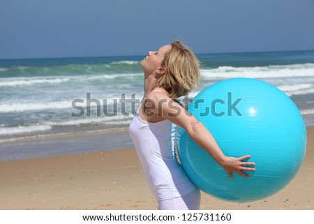 Exercises with blue ball on the beach