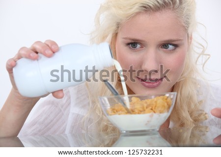 Woman pouring milk into cereal bowl