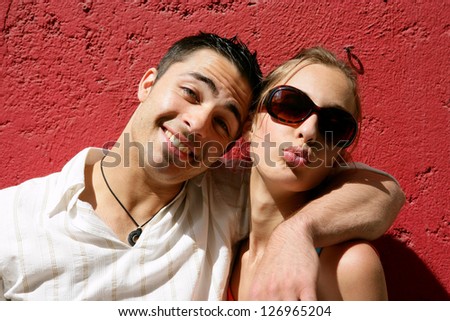 Cool couple posing against a red wall