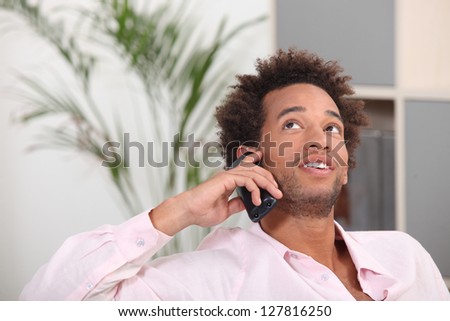 young Afro-American talking on his cell at home