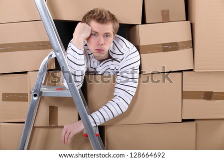 Man stuck behind stacks of cardboard boxes