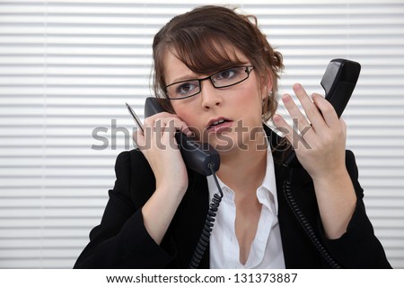 Stressed office worker with two telephones