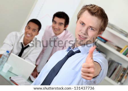 Young businessman giving thumbs-up during meeting