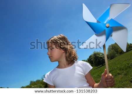 Little girl stood in filed with toy windmill