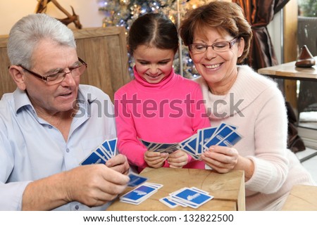 Little girl playing cards with her grandparents