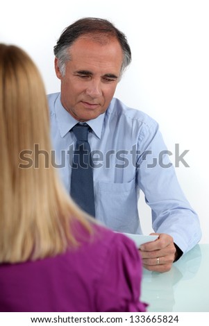 mature businessman in office with young woman back turned