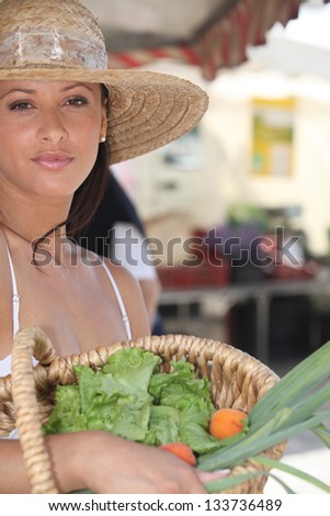 Summery woman in a straw hat holding a basket of market produce