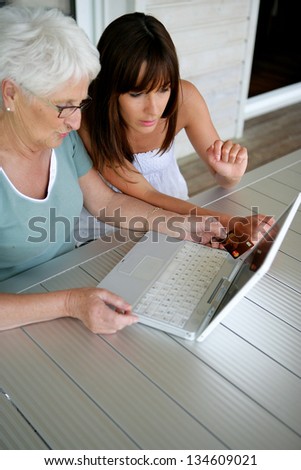 Young woman teaching her grandmother computer skills