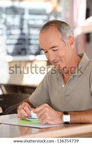 Grey-haired man sat in cafe drinking espresso