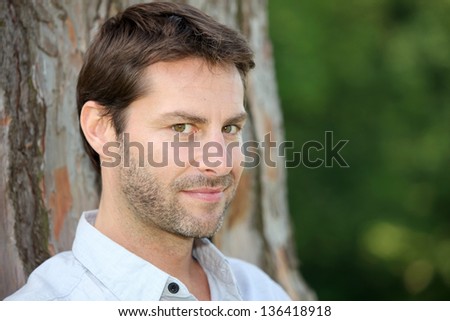 Portrait of man in front of tree trunk