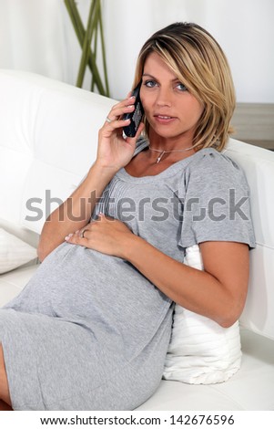 Pregnant woman sitting on the sofa with a telephone