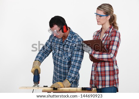 Man using band saw whilst woman supervises