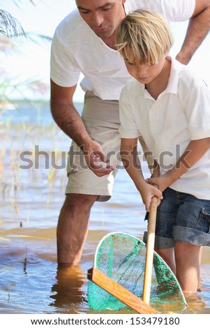 Father teaching son to fish with net