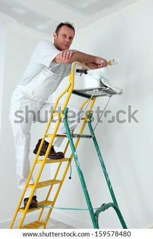 Painter climbing ladder to paint ceiling
