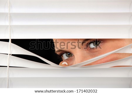 Woman peeking through  blinds