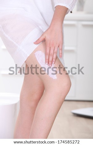 a woman applying cream on her leg