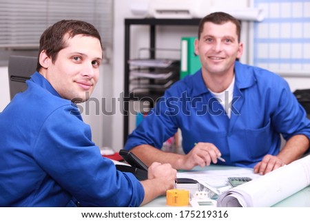 Two manual worker in the office checking stock levels