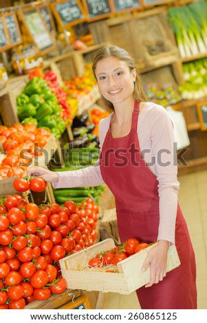 Shop worker carrying a crate of tomatoes