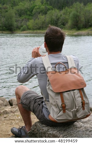 Young man on a trekking day drinking water from bottle
