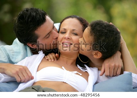 Father and son kissing woman on the cheek