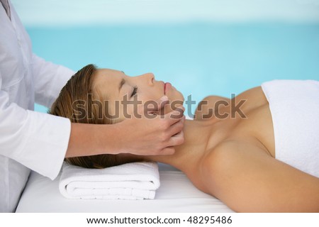Woman having face massage by a swimming pool