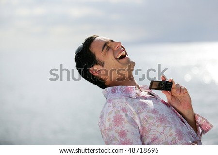 Man laughing on the phone by the sea