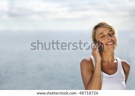 Blonde woman talking on the phone by the sea
