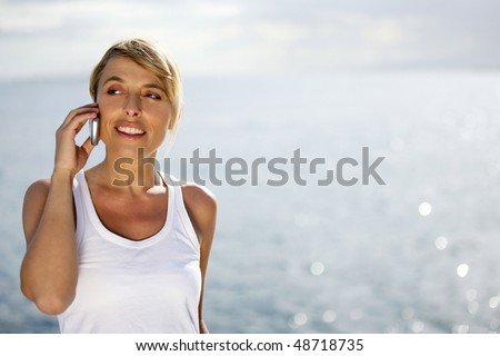 Blonde woman talking on the phone by the sea