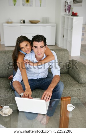A man and a woman smiling in front of a laptop computer