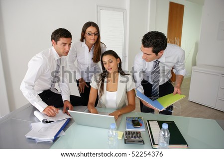 Women in front of a computer next to men in an office
