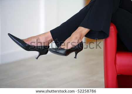 Woman sat on a red armchair wearing shoes with heels