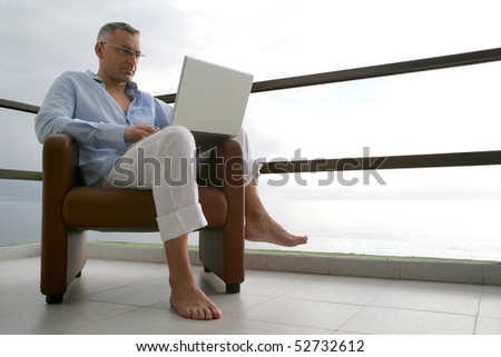 Man sitting in an armchair with a laptop computer