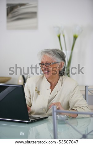 Portrait of a smiling senior woman in front of a laptop computer