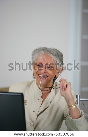 Portrait of a smiling senior woman in front of a laptop computer