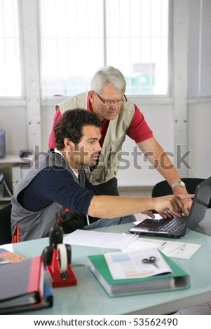 Portrait of two men in an office watching a laptop computer screen