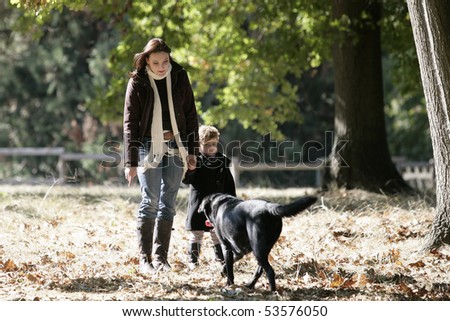 A woman and a little girl having a walk with a dog