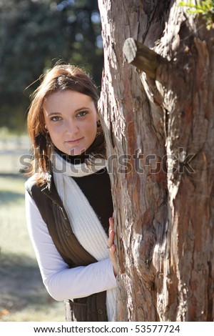 Portrait of a young woman hidden behind a tree