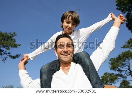 Portrait of a little boy sitting on the shoulders of a man