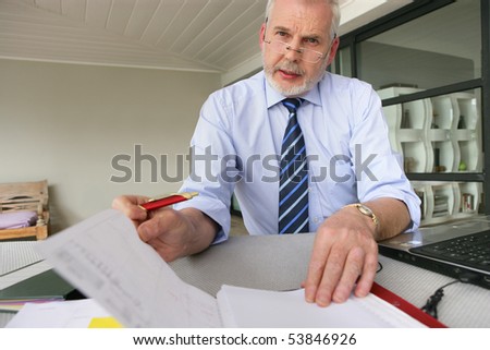 Portrait of a senior man with a laptop computer and documents