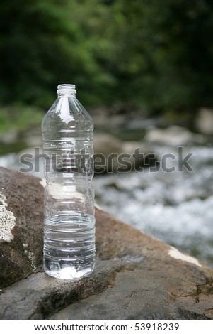 A bottle of water on a stone next to a river