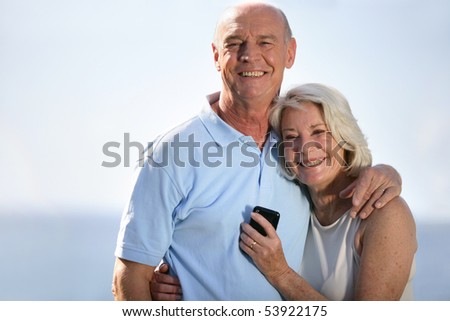 Portrait of a couple of smiling seniors with a phone