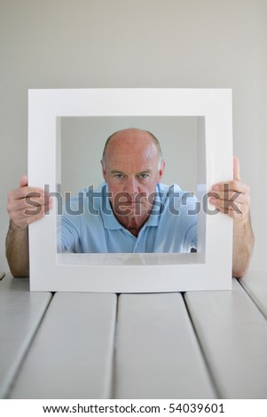 Portrait of a senior man behind a white frame