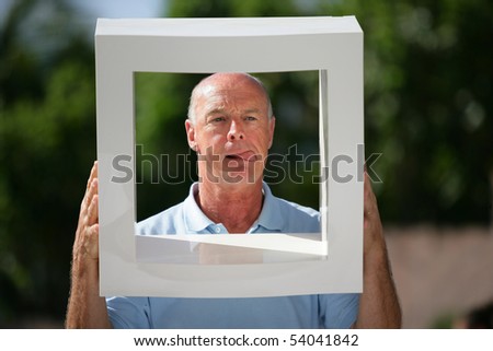 Portrait of a senior man from behind a white frame