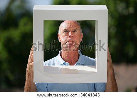 Portrait of a senior man from behind a white frame
